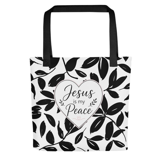 Front view of a black and white Christian tote bag with black handles, leafy pattern, and a heart design that says “Jesus is my Peace.”