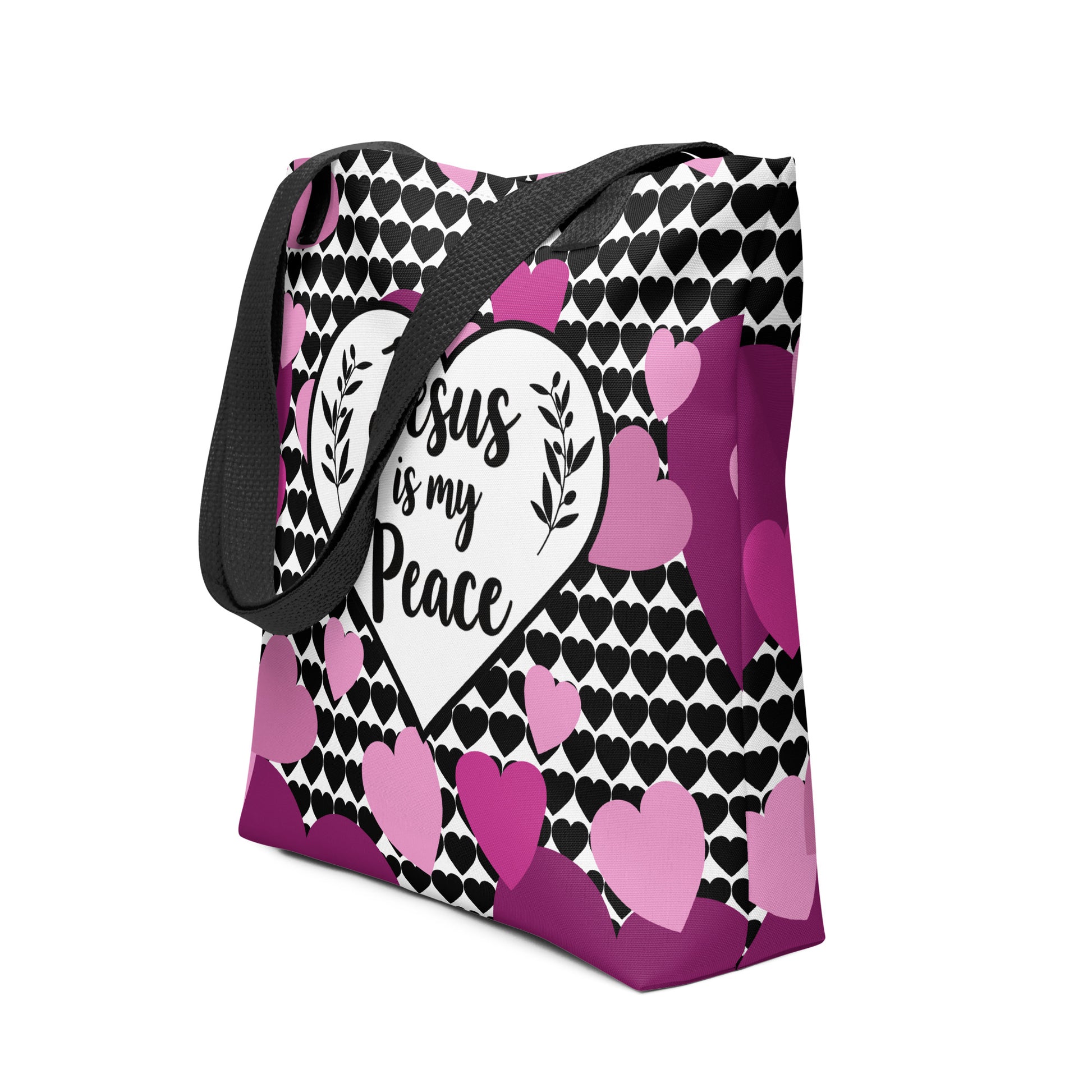 Angled view of the heart-print tote with black handles, showing the “Jesus is my Peace” message in a white heart and scattered pink/purple hearts.