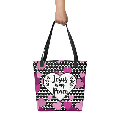 Tote bag held by hand with black straps, displaying a black-and-white heart background and a central “Jesus is my Peace” heart graphic with pink/purple hearts.