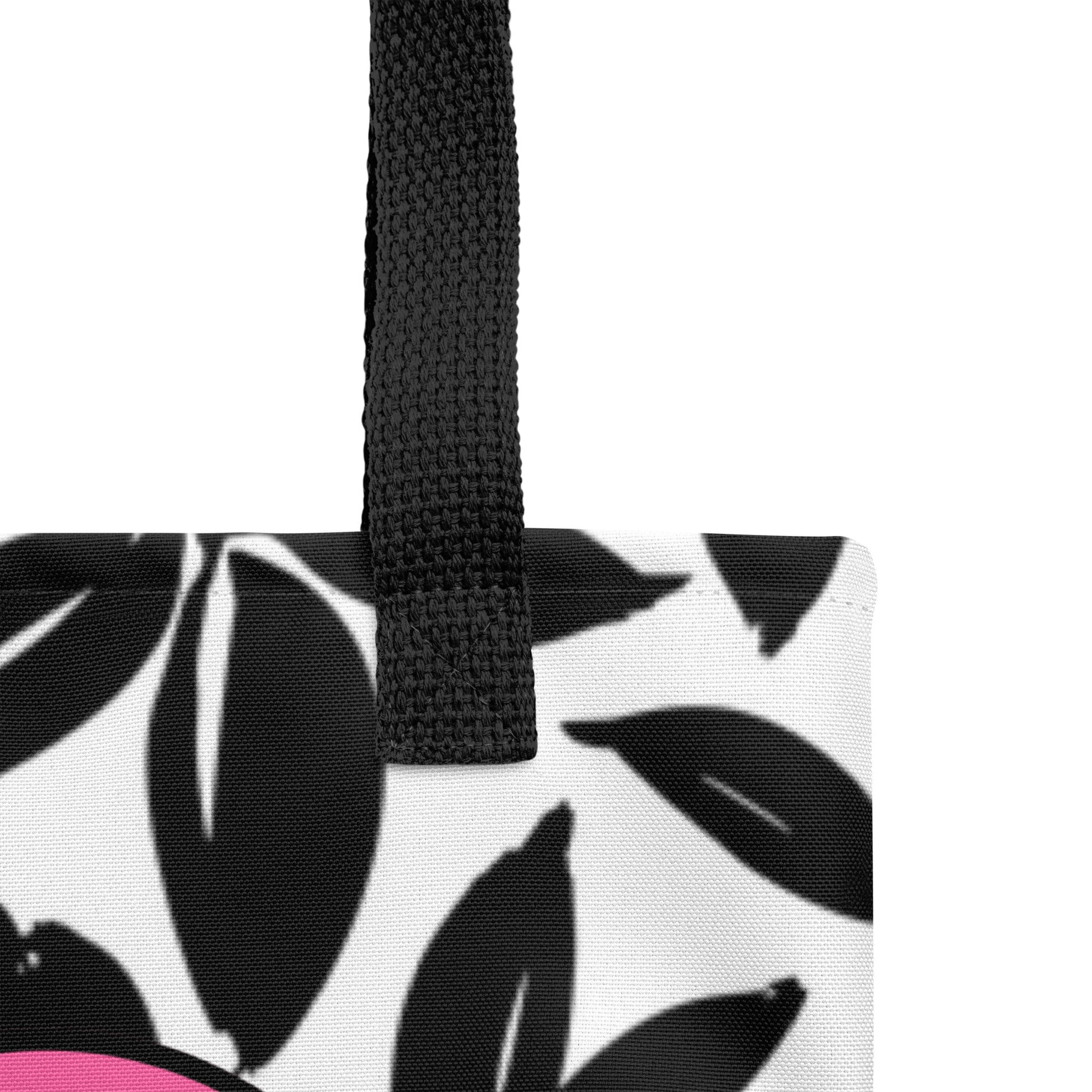Close-up of tote bag canvas and black strap stitching over the black leaf print fabric near the pink heart design.