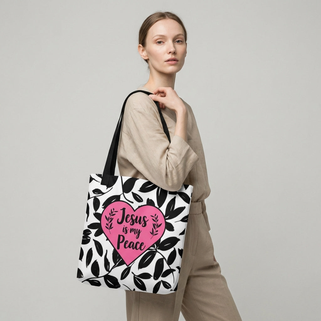 Lifestyle shot of a person carrying the black leaf print tote with black straps and a pink heart reading “Jesus is my Peace.”