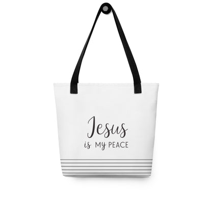 White tote bag hanging on a hook with “Jesus is my peace” in dark gray and gray horizontal stripes at the bottom.