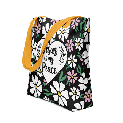 Angled view of the black flower-print tote with yellow handles, showing the “Jesus is my Peace” heart design and colorful floral pattern.