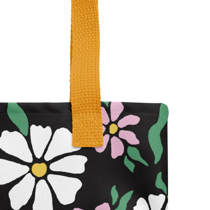 Close-up of the black floral tote fabric and mustard yellow strap, highlighting the stitching, textured canvas, and flower pattern detail.