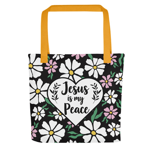 Front view of a black floral tote bag with mustard yellow straps featuring a white heart graphic that reads “Jesus is my Peace.”