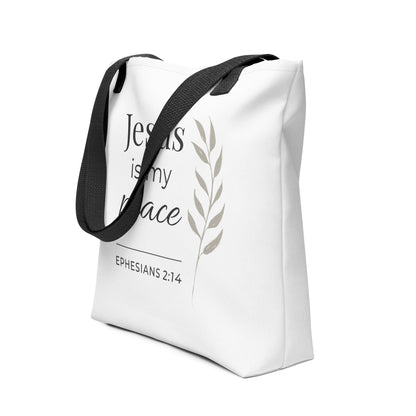 Angled view of a white tote bag with black handles featuring “Jesus is my peace,” “Ephesians 2:14,” and a leaf design in dark gray.
