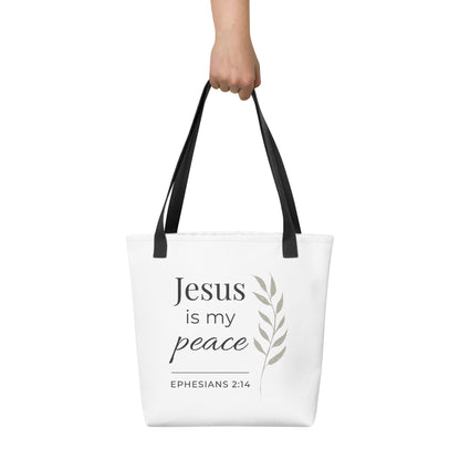 White tote bag held in hand with black handles featuring “Jesus is my peace,” “Ephesians 2:14,” and a leaf design in dark gray.