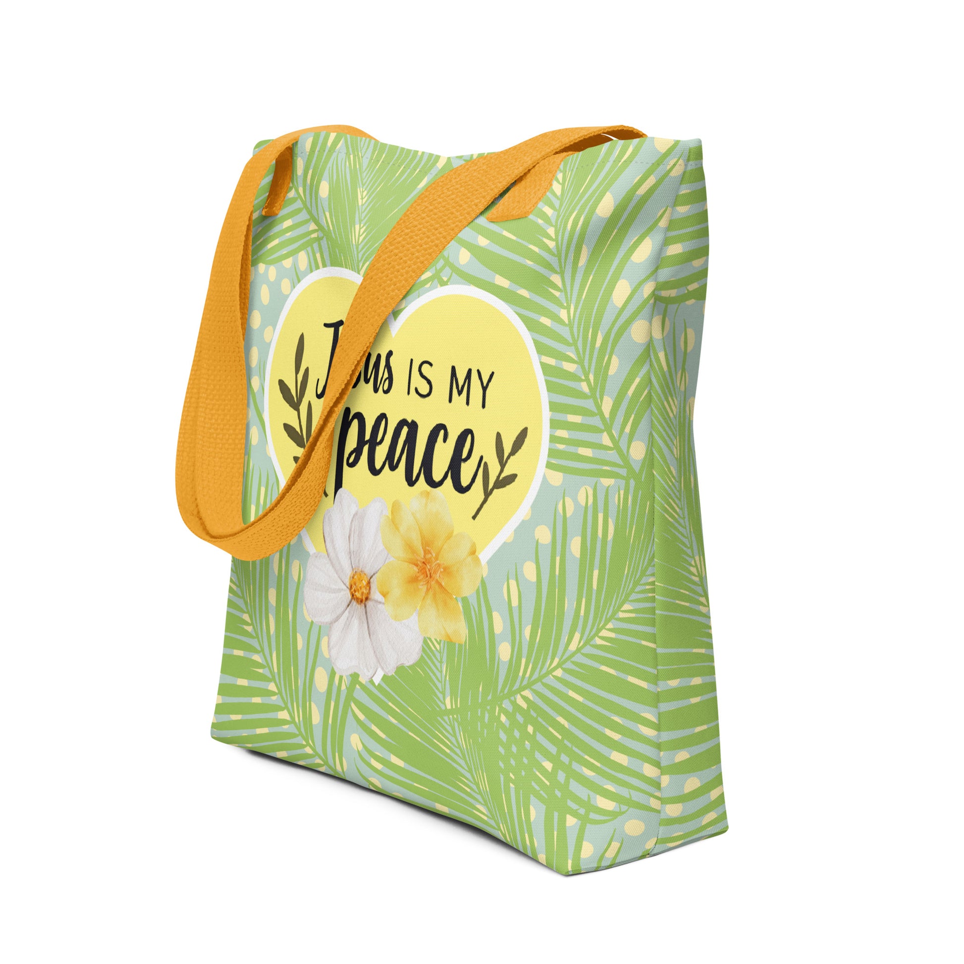 Angled view of the palm-leaf tote bag showing the yellow handles and the “Jesus is my peace” heart-and-flowers design on the front.