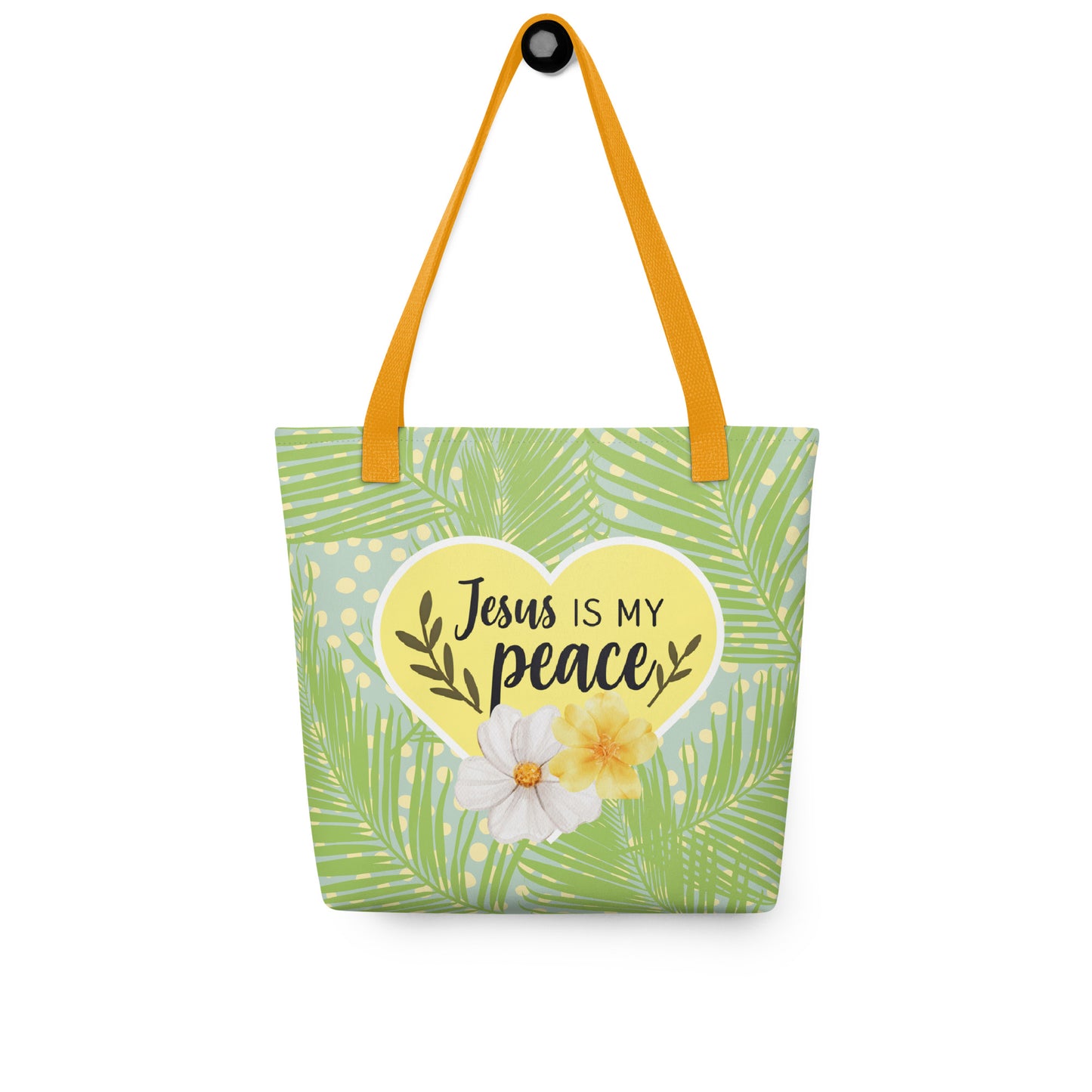 Tote bag hanging on a hook with mustard-yellow straps, green palm fronds and dots, and a yellow heart that says “Jesus is my peace.”
