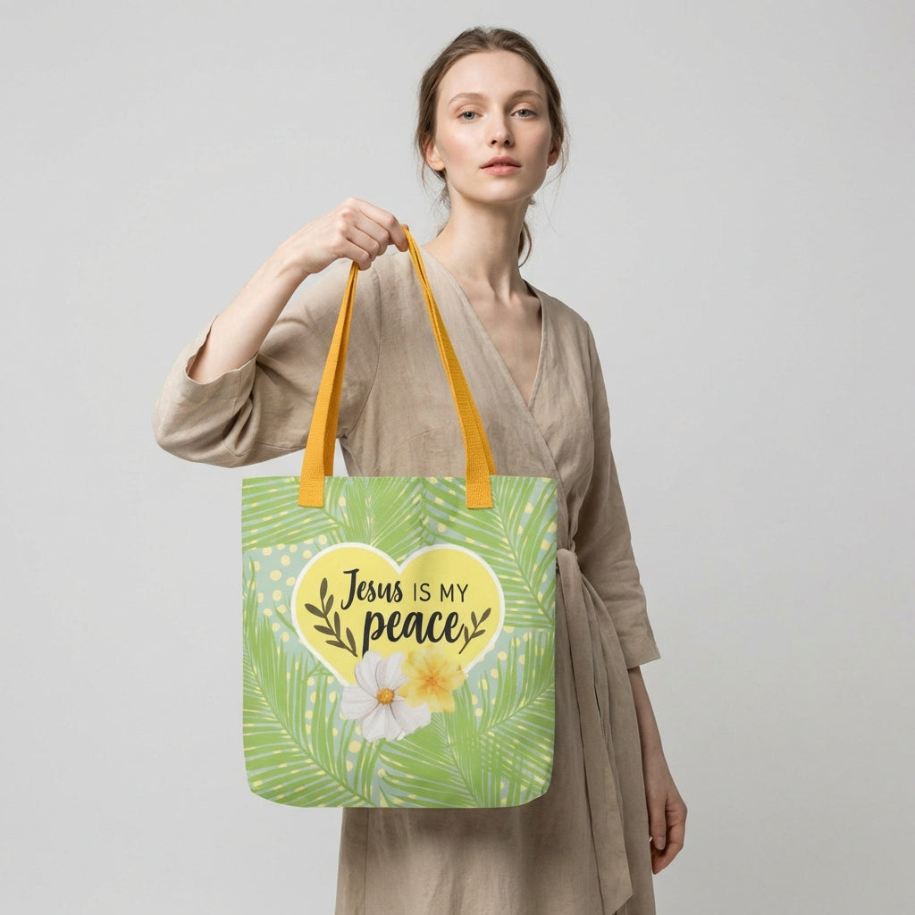 Lifestyle photo of a person carrying the palm-leaf tote bag with yellow straps and a heart design that says “Jesus is my peace,” accented with flowers.