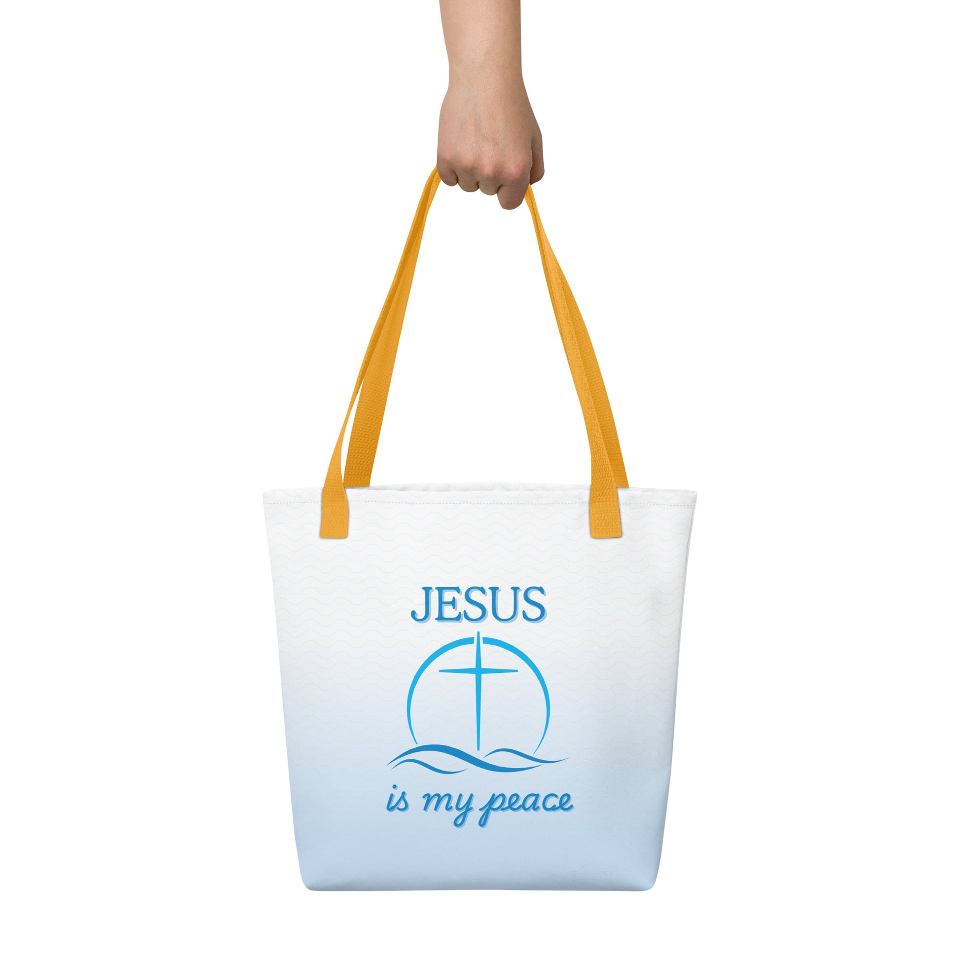 Close carry shot of the tote held by the yellow handles, showing the blue waves and “JESUS is my peace” cross-and-waves artwork.