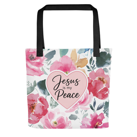 Front view of a floral Christian tote bag with black handles, pink watercolor flowers, and a heart design that says “Jesus is my Peace.”