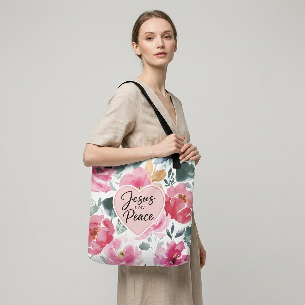 Model carrying a floral Christian tote bag with black handles, pink flower artwork, and a “Jesus is my Peace” heart design.