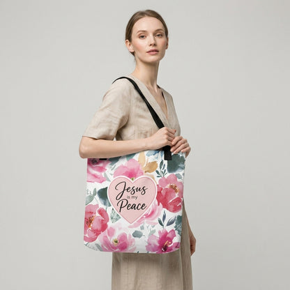 Model carrying a floral Christian tote bag with black handles, pink flower artwork, and a “Jesus is my Peace” heart design.