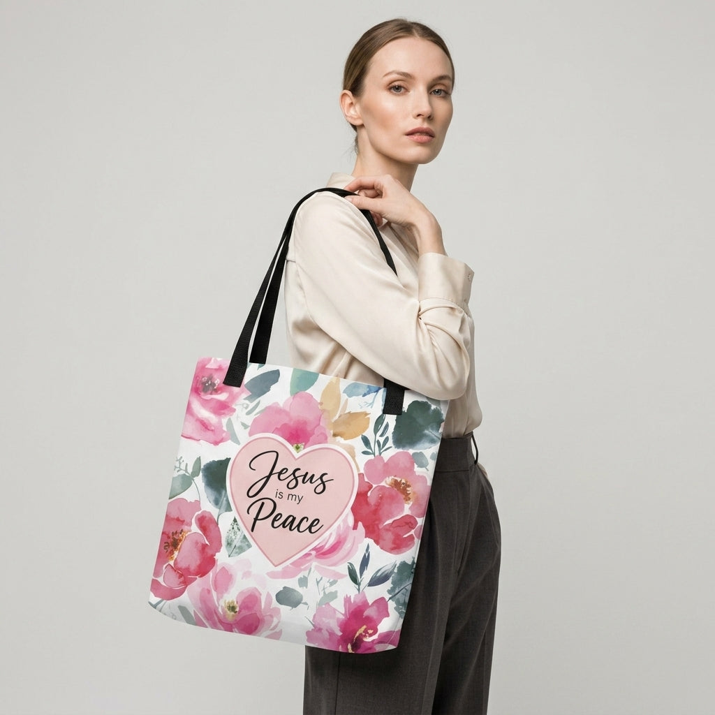 Model carrying a floral Christian tote bag with black handles, pink flower artwork, and a “Jesus is my Peace” heart design.