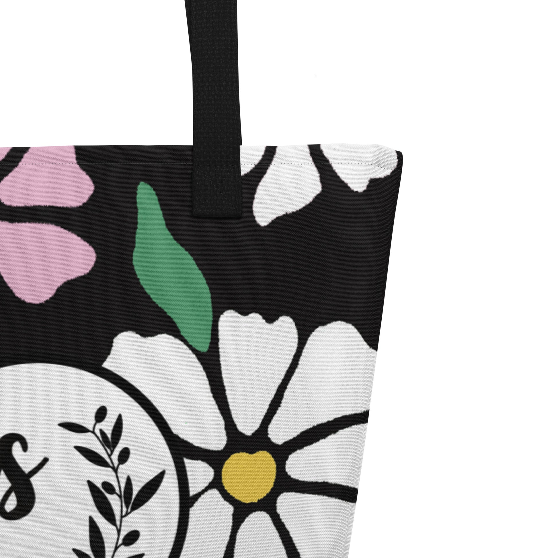 Close-up of black woven handle and stitched top edge on the black fabric with colorful floral print.