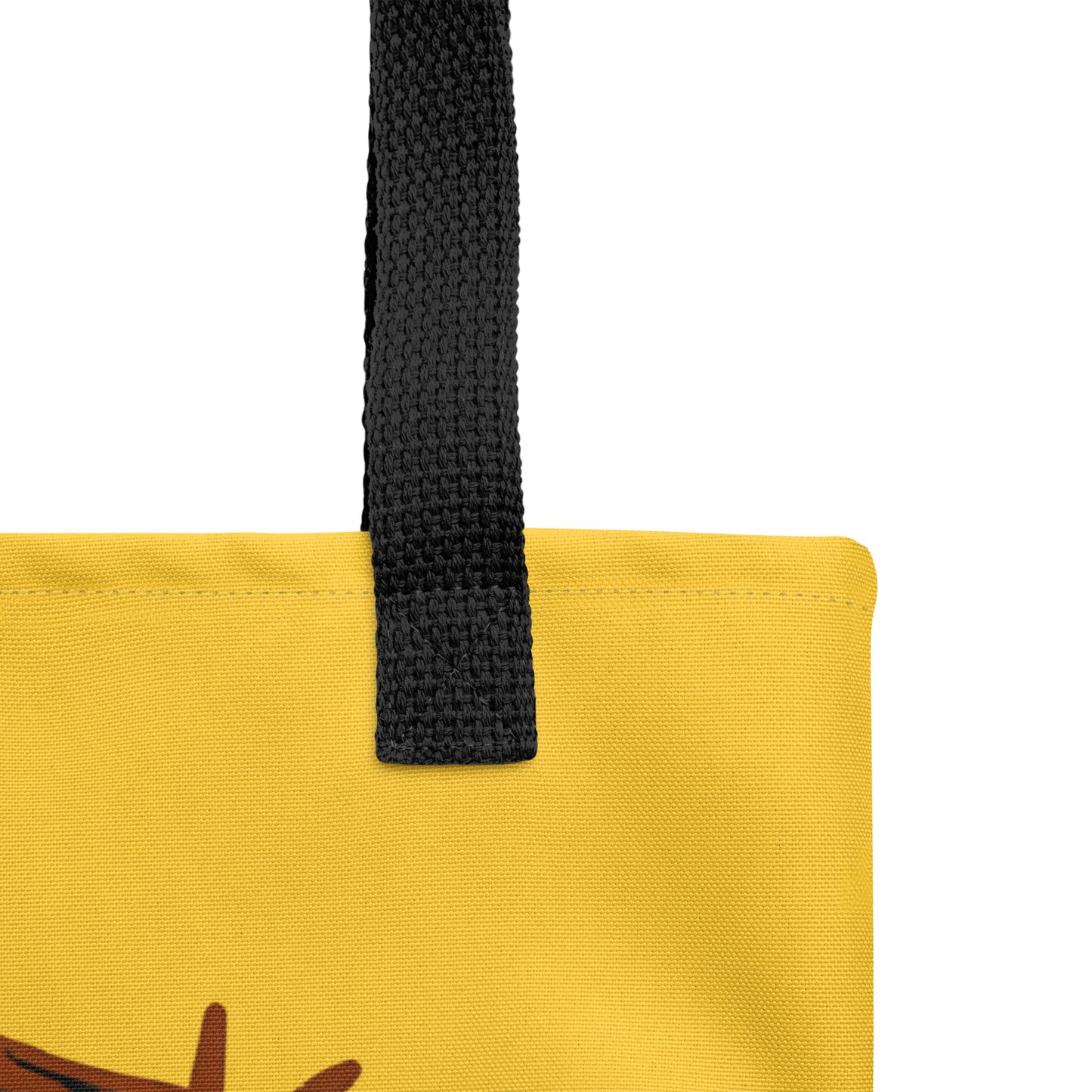 Close-up of black woven handle and stitched top edge on the yellow tote bag fabric.