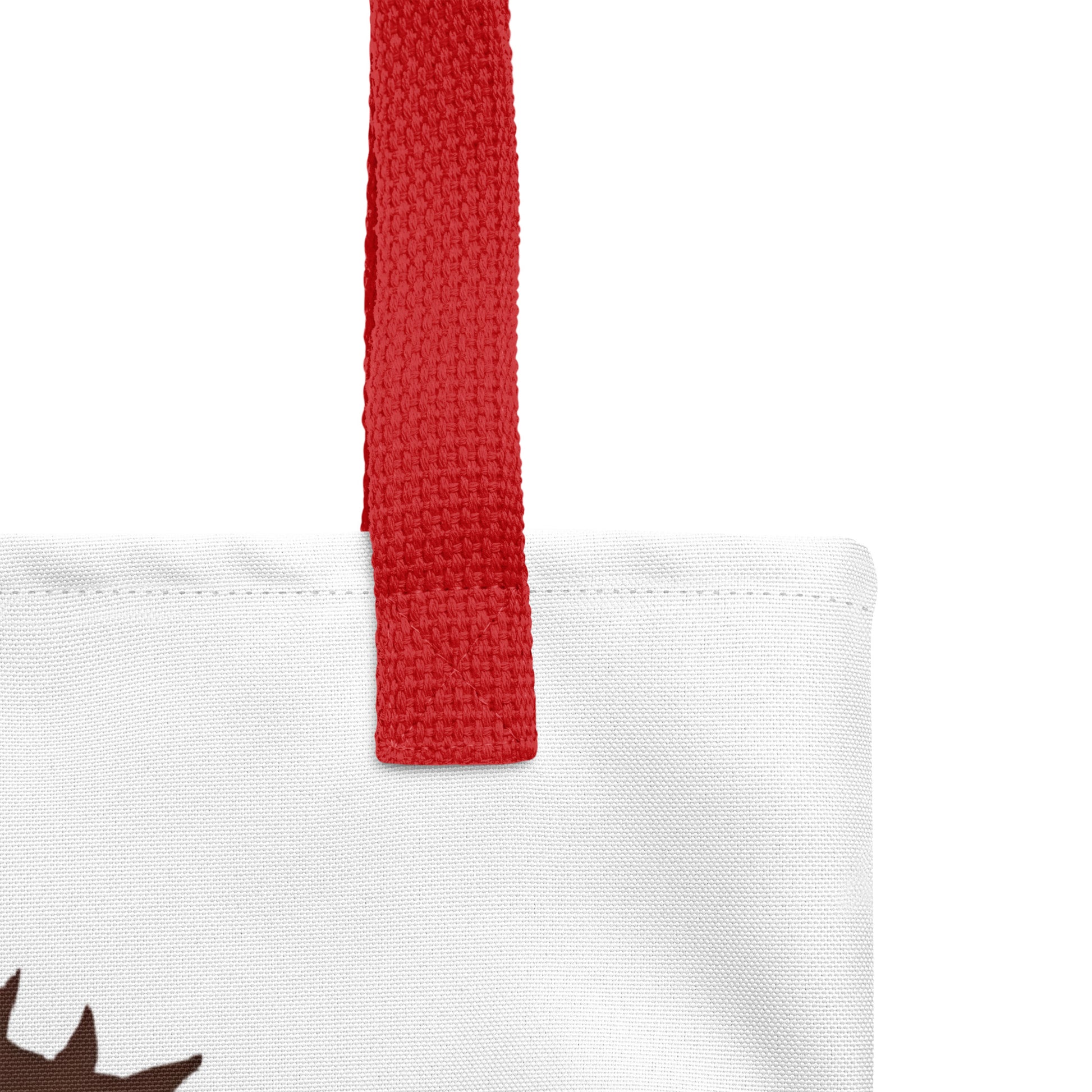 Close-up of the white tote fabric and red strap, highlighting the stitching, textured canvas, and strap weave detail.