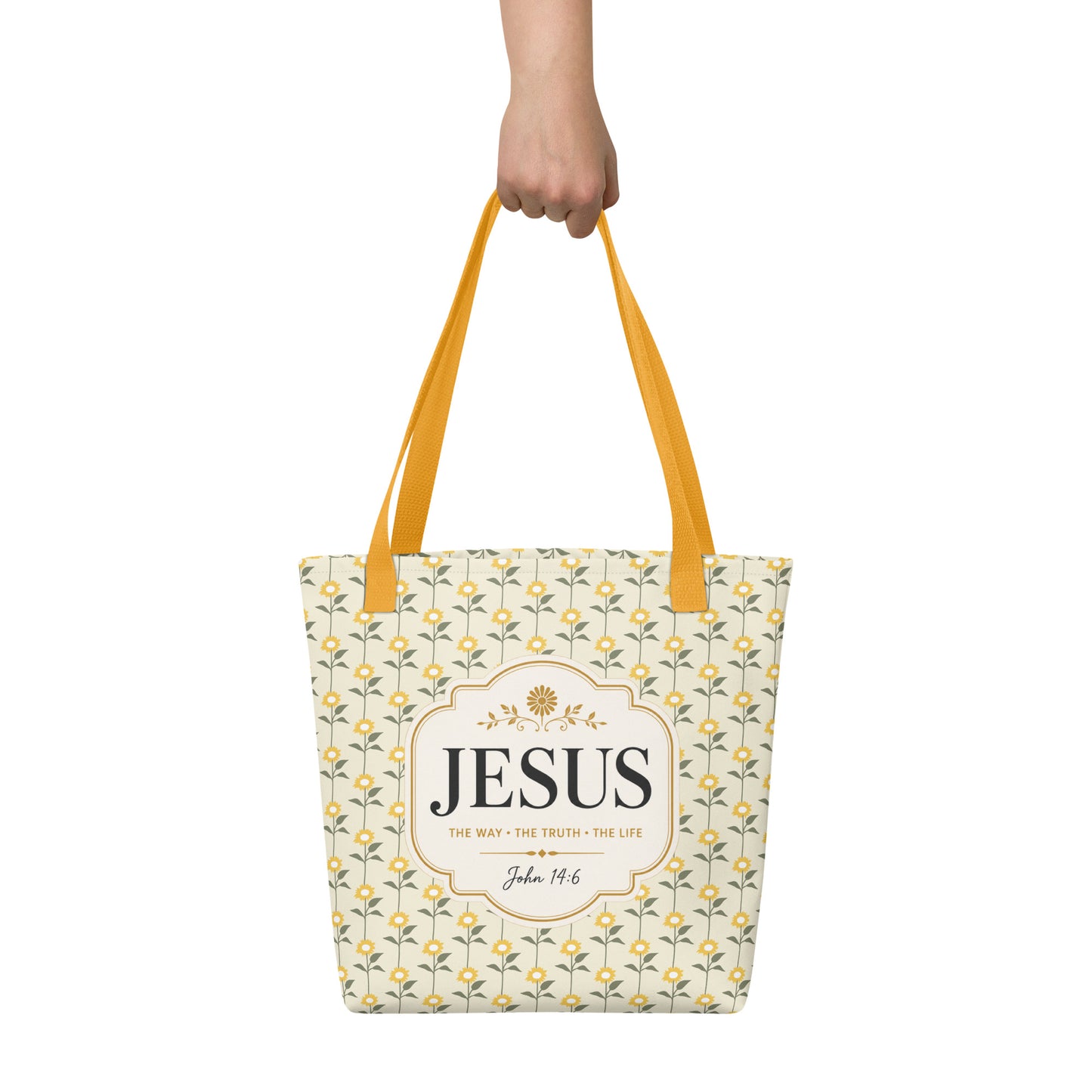 Person holding a Christian tote bag with yellow handles, yellow sunflower details, and “Jesus, The Way, The Truth, The Life” lettering