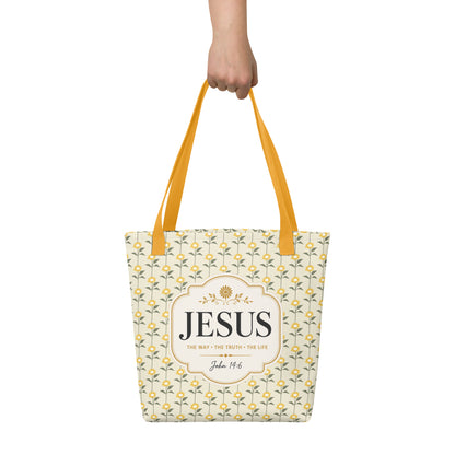 Person holding a Christian tote bag with yellow handles, yellow sunflower details, and “Jesus, The Way, The Truth, The Life” lettering