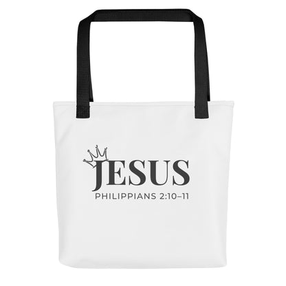 White tote bag with black handles featuring “JESUS,” a crown graphic, and “Philippians 2:10–11” in black text.