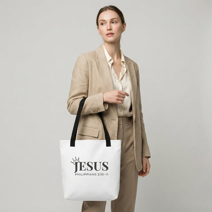 Model holding a white tote bag featuring “JESUS,” crown icon, and “Philippians 2:10–11.”