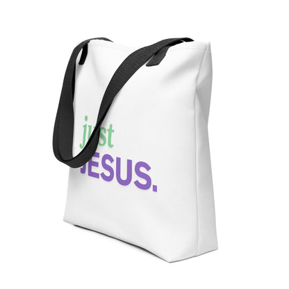Angled view of a white tote with black straps showing the “just JESUS.” design in green and purple.