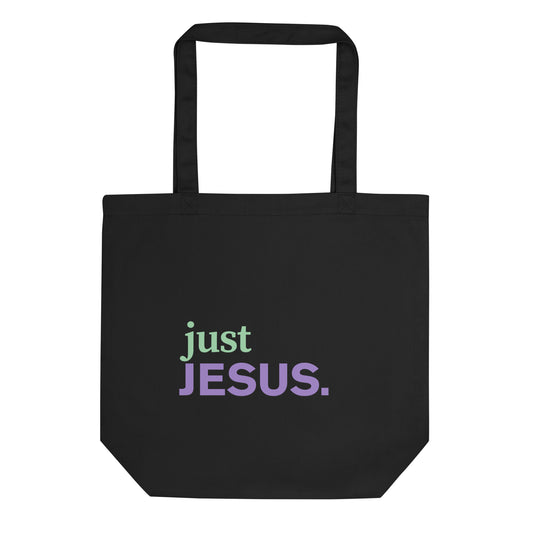 Black cotton tote bag with “just JESUS.” printed on the front in green and purple text.