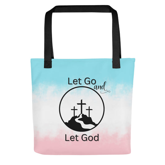 Front view of a tote bag with black handles, a blue-to-pink gradient background, and “Let Go and Let God” with a cross-and-mountain graphic.