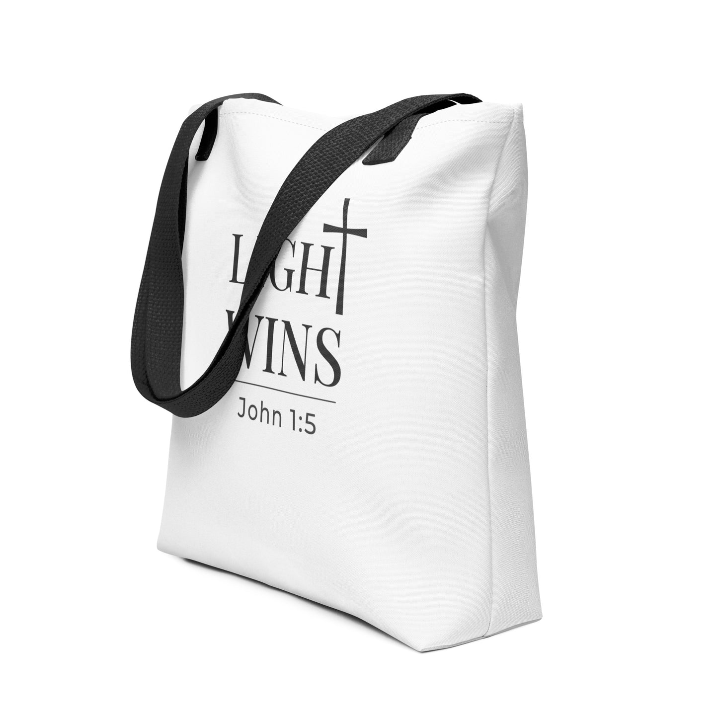 White Christian tote shown at an angle with dark gray “Light Wins” lettering, cross icon, and the verse “John 1:5.”