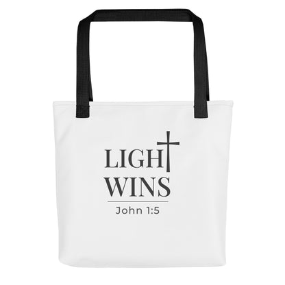 White tote bag with black handles featuring “Light Wins,” a cross graphic, and “John 1:5” in dark gray text.