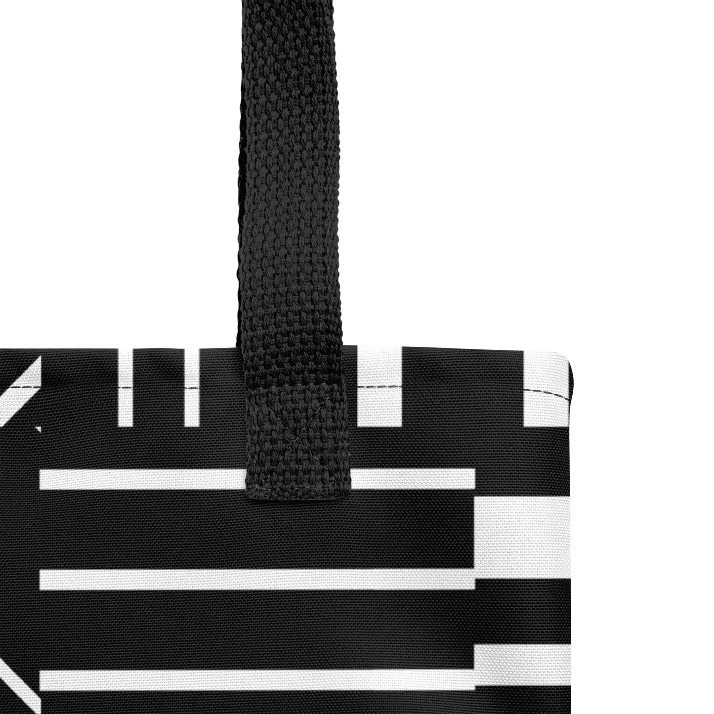 Close-up of the black-and-white striped tote fabric and black strap, highlighting the stitching, textured canvas, and bold geometric pattern.