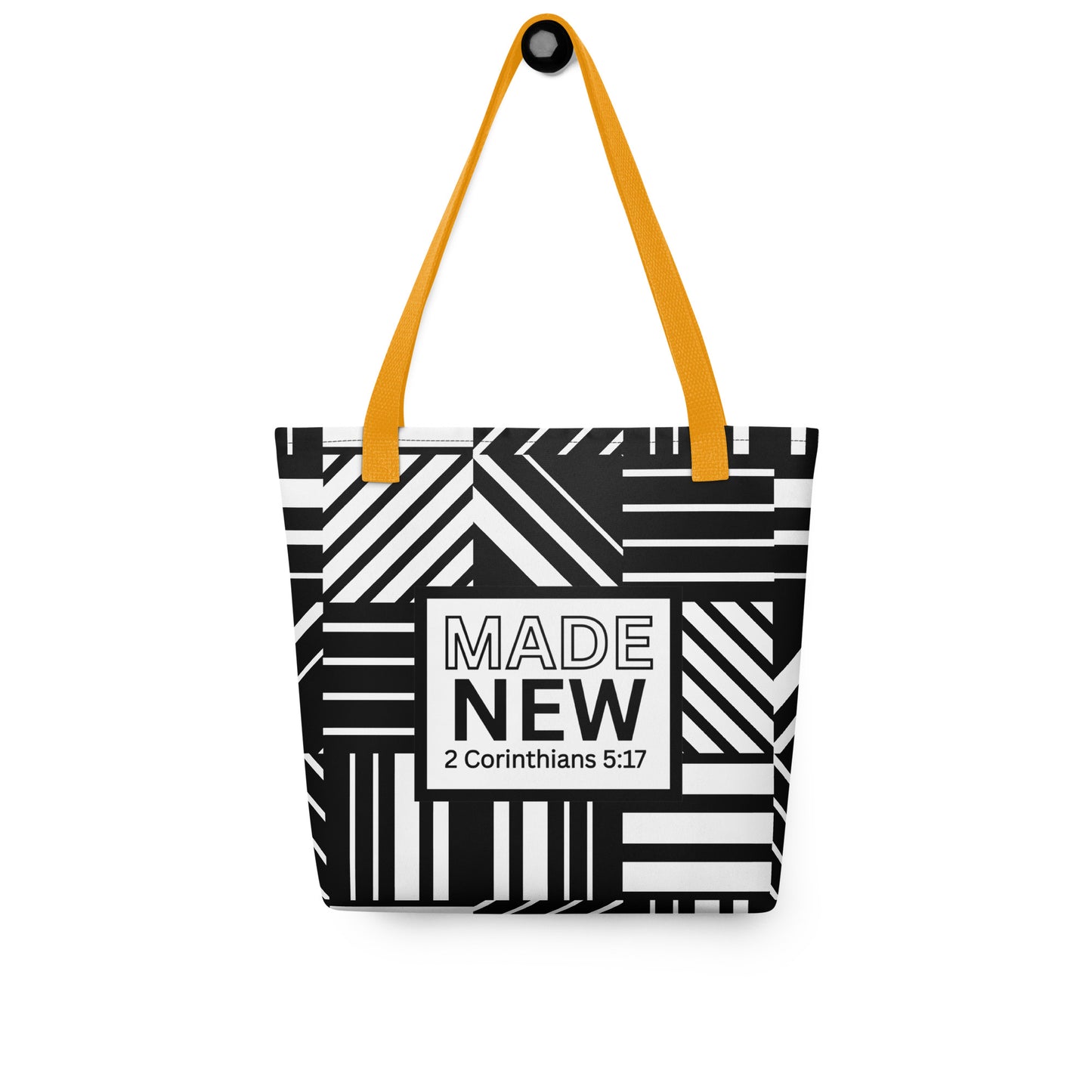 Tote bag with yellow handles hanging on a hook, displaying the black-and-white geometric pattern and “MADE NEW — 2 Corinthians 5:17” design.