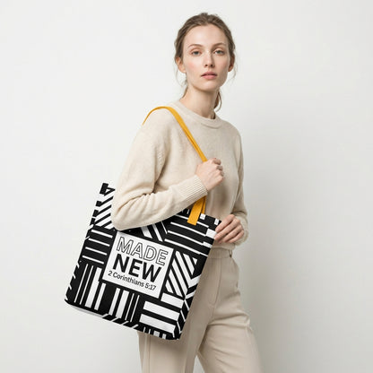 Model carrying a black-and-white geometric patterned tote with yellow handles and the centered “MADE NEW — 2 Corinthians 5:17” design.