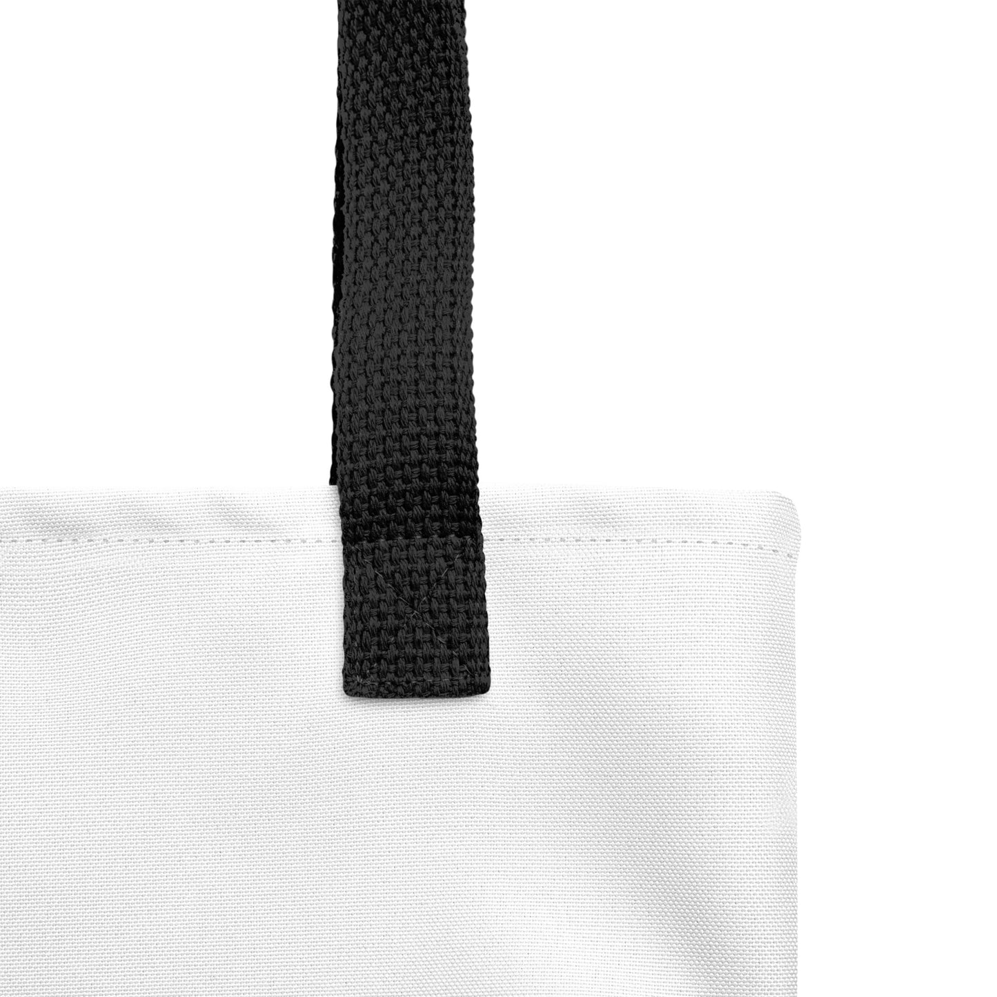 Close-up of the white tote fabric and black strap, highlighting the stitching, textured canvas, and strap weave detail.