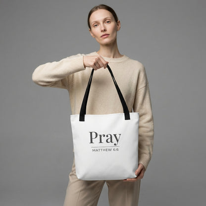 Model holding a white tote bag with dark gray “Pray” and “Matthew 6:6” printed on the front.