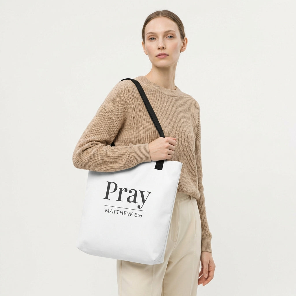 Model holding a white tote bag with dark gray “Pray” and “Matthew 6:6” printed on the front.
