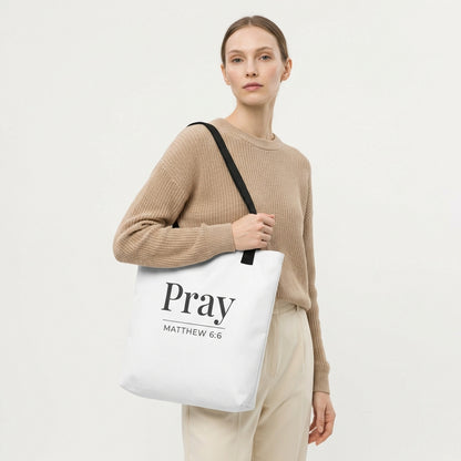 Model holding a white tote bag with dark gray “Pray” and “Matthew 6:6” printed on the front.