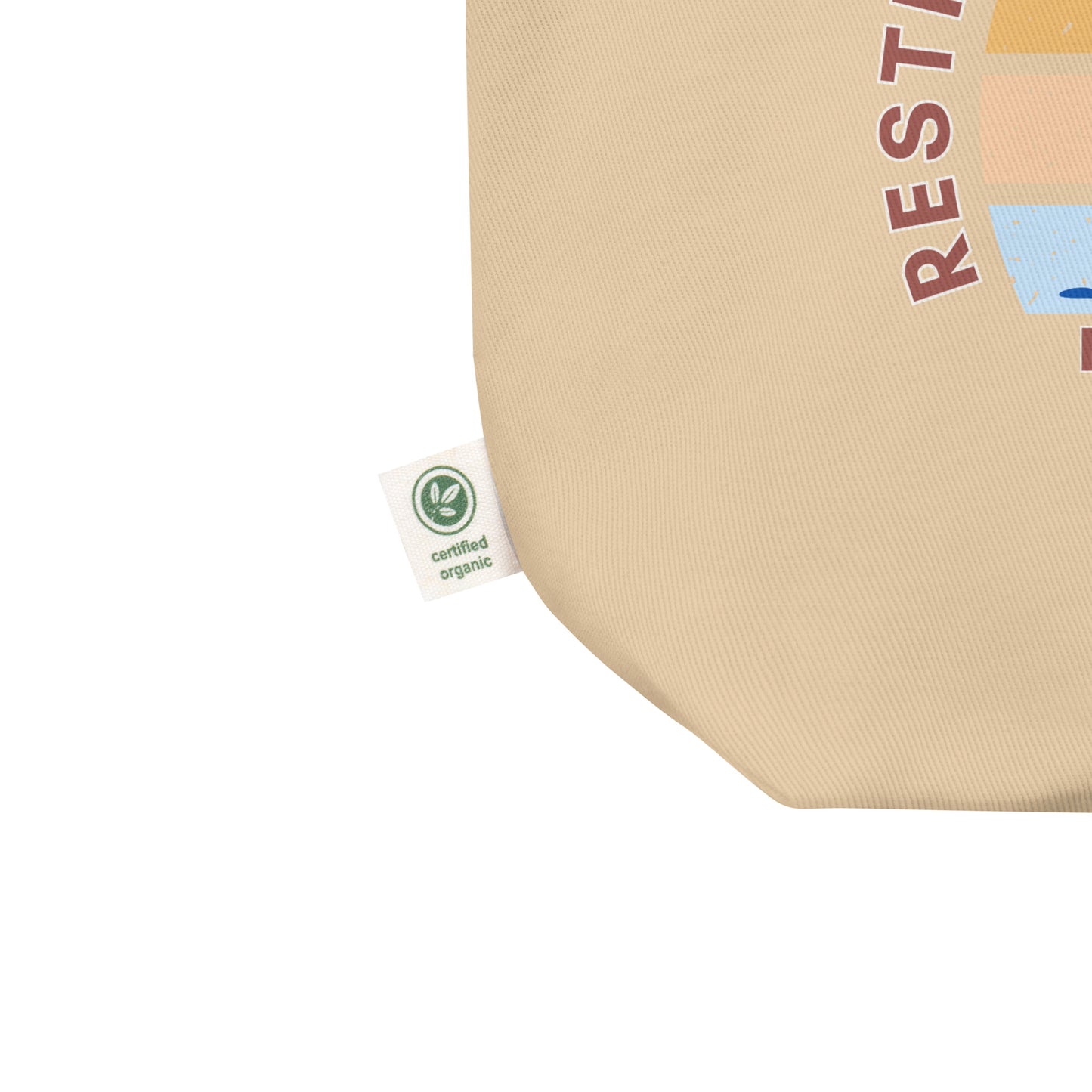 Close-up of the natural cotton tote fabric, showing the textured weave and a side “certified organic” tag detail.
