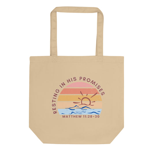 Front view of a cotton tote bag featuring “Resting in His Promises,” “Matthew 11:28–30,” and a sunset-over-waves graphic.