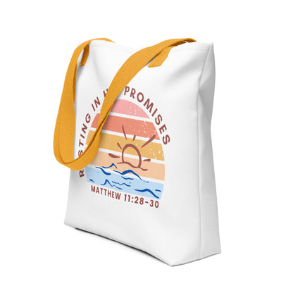 Angled view of the white tote with yellow handles, showing the vintage-style sunset circle, ocean waves, and “RESTING IN HIS PROMISES” design with “MATTHEW 11:28–30.”