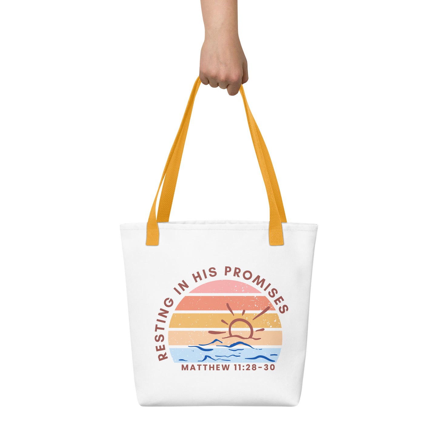Tote bag held by hand with yellow straps, featuring a retro sunset graphic over blue waves and the Bible verse reference “MATTHEW 11:28–30” under “RESTING IN HIS PROMISES.”