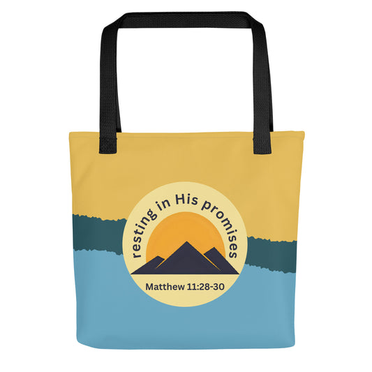 Front view of tote bag with black straps, yellow and blue color-block design, and circle mountain graphic reading “resting in His promises” and “Matthew 11:28–30.”