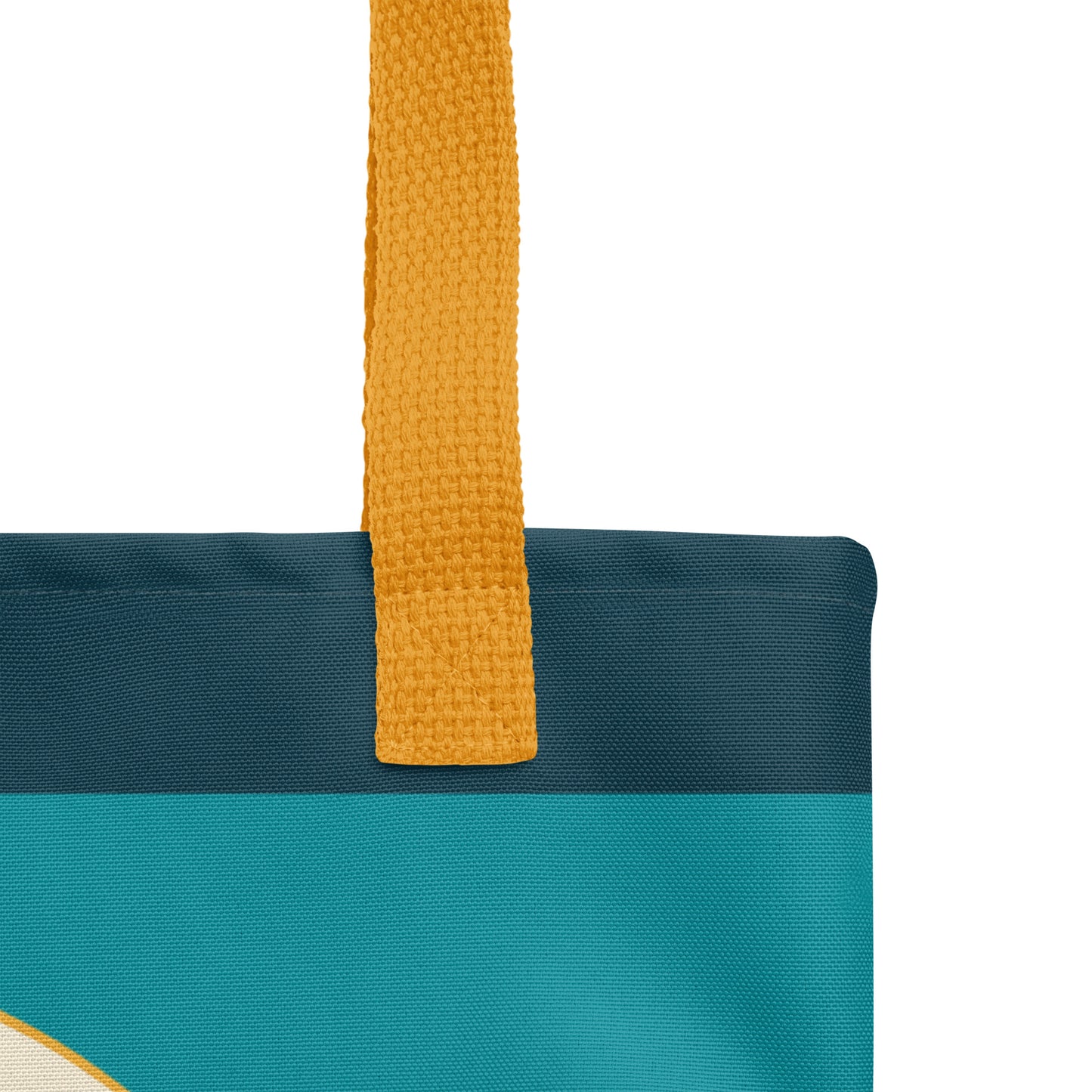 Close-up of a teal Christian tote bag showing the yellow woven handle, fabric texture, dark teal top border, and part of the mountain design.