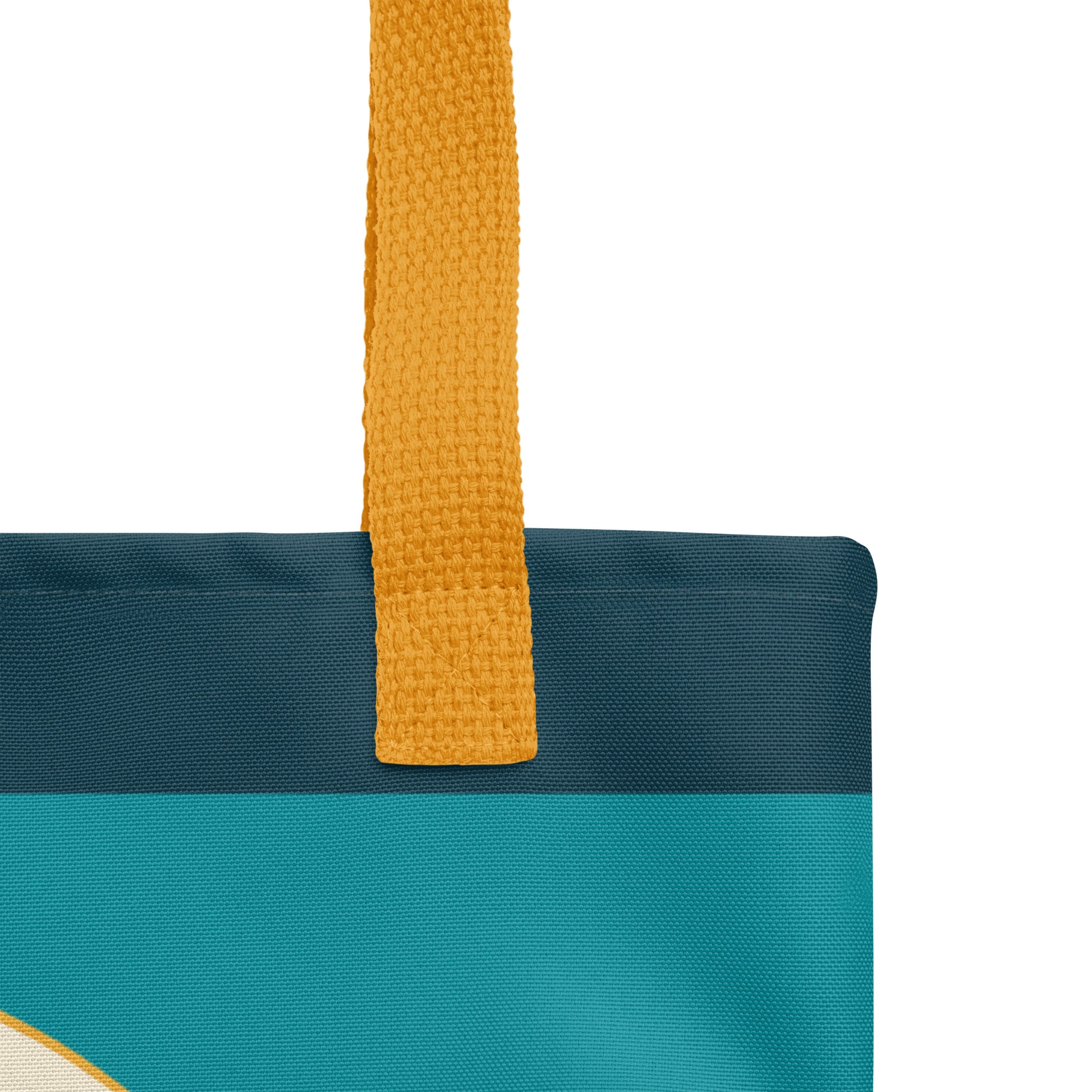 Close-up of a teal Christian tote bag showing the yellow woven handle, fabric texture, dark teal top border, and part of the mountain design.