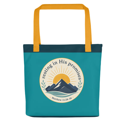 Front view of a teal Christian tote bag with yellow handles, a mountain and sunrise design, and the text “Resting in His Promises Matthew 11:28-30.”