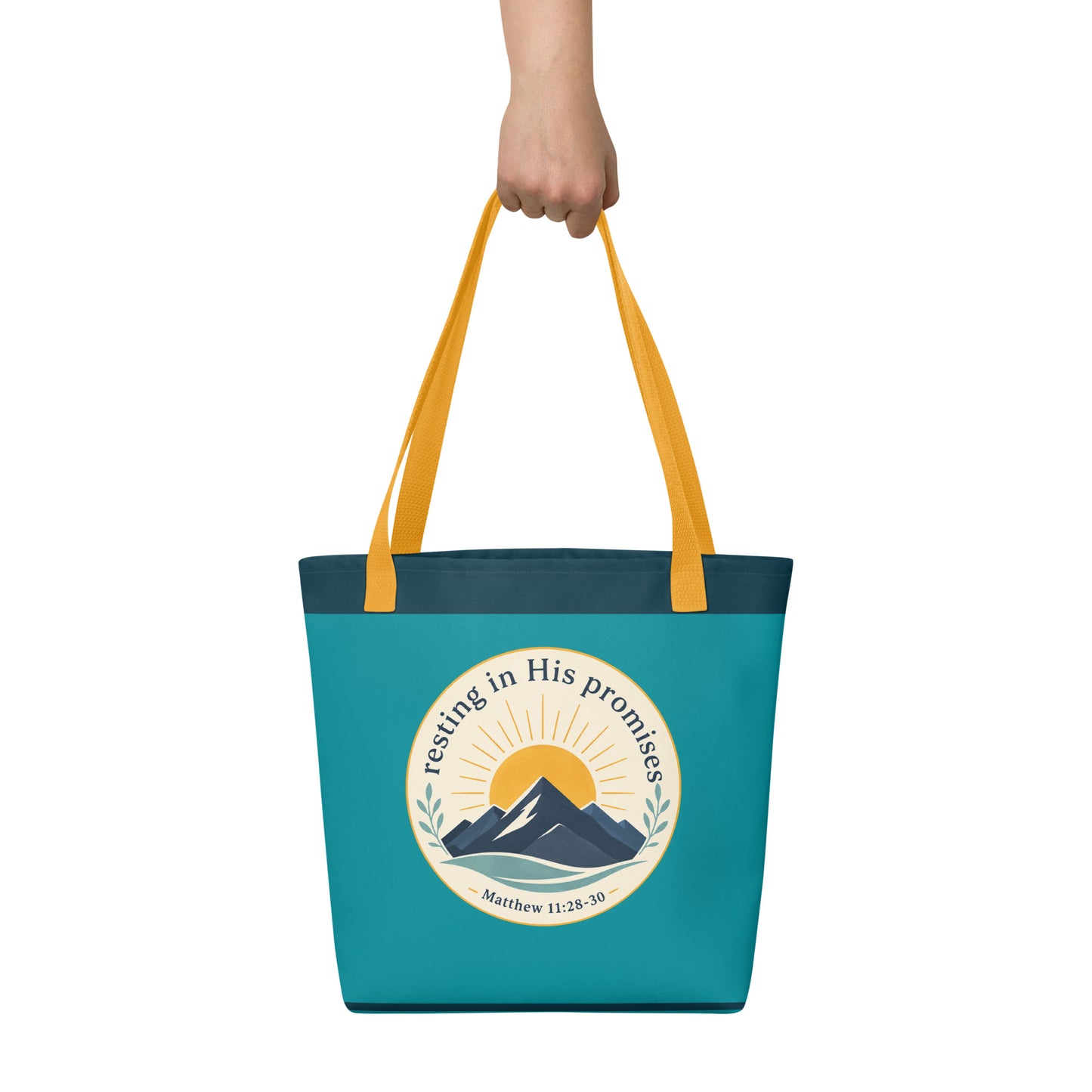 Person holding a teal Christian tote bag with yellow handles, mountain artwork, and the Bible verse reference Matthew 11:28-30.