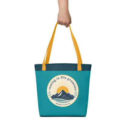 Person holding a teal Christian tote bag with yellow handles, mountain artwork, and the Bible verse reference Matthew 11:28-30.