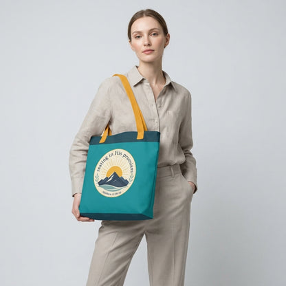 Model carrying a teal Christian tote bag with yellow handles and a faith-inspired mountain design featuring Matthew 11:28-30.