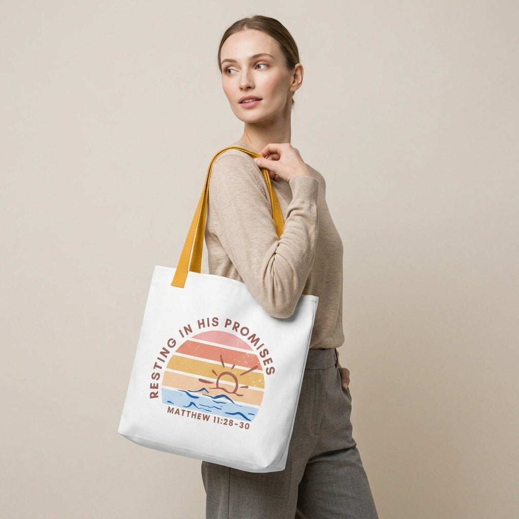 Model carrying a white tote with mustard yellow straps, featuring a retro sunset ocean design and the message “RESTING IN HIS PROMISES” (Matthew 11:28–30) on the front.